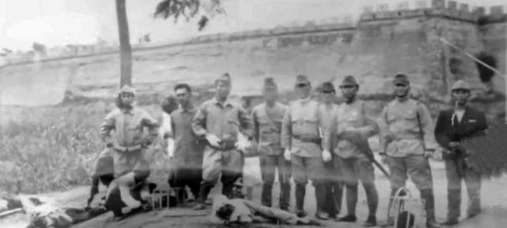 Image depicts a group of Japanese soldiers standing behind the remains of two beheaded Chinese prisoners, their heads placed in some sort of cage, in front of the Great Wall of China. The Japanese soldiers appear to be wearing an older "Showa Type 05" uniform, likely dating the image to the late 1930s.