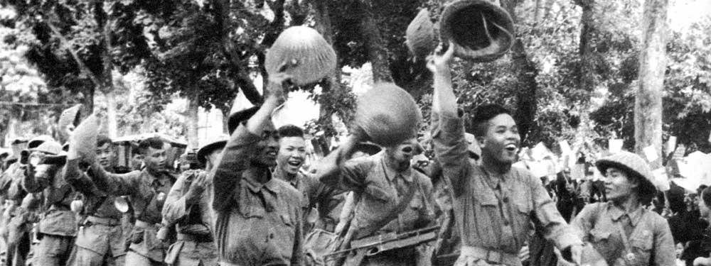 October 9, 1954. Waving to the city's populace, joyous Viet Minh troops enjoy a "parade of victory" through the streets of Hanoi following the French withdrawal. Thousands of Vietnamese civilians crowded the capital's streets, waving flags, cheering, and throwing flowers to the crowd of soldiers. »