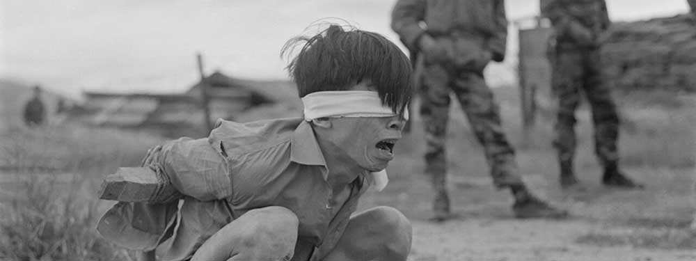 Captured Viet Cong soldier, blindfolded and tied in a stress position by American forces during the Vietnam War, 1967